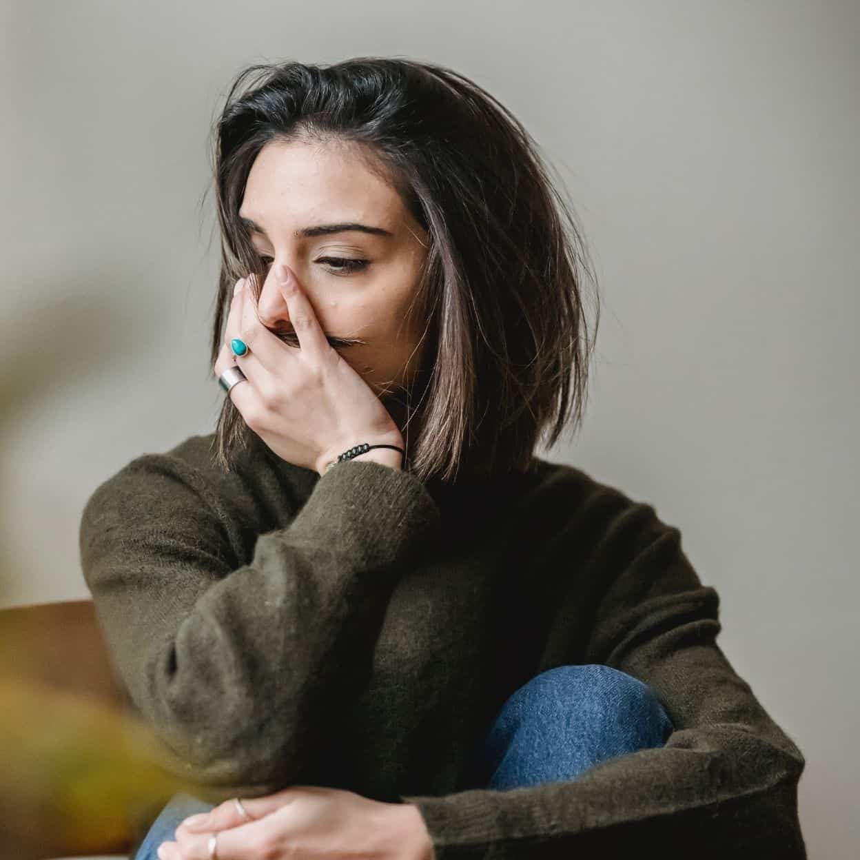 Image Of A Woman With Her Arm Around Her Knees And Covering Her Face. Have You Been Searching "anxiety Therapist Near Me"? Then We Can Help You With Stress Management. Contact Us To Begin Anxiety Treatment In Asheville, Nc 28714.