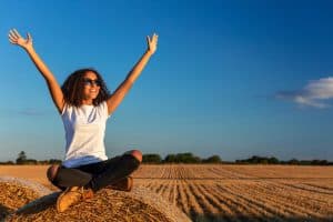 Image of a woman in a white shirt free from trauma symptoms sitting on a hay bale. You can find a "trauma therapist near me" anywhere in Asheville, NC with teletherapy. Our goal in trauma therapy is to help you identify and address your PTSD symptoms and triggers. If you are ready to make a PTSD treatment plan in Charlotte, Raleigh, or somewhere else in North Carolina we are here for you.
