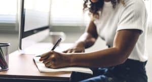A close-up of a person writing a note at their computer desk. This could represent how an Asheville mental health therapist can help you address ADHD. Learn how Asheville therapists can help you address ADHD symptoms in Asheville, NC today.